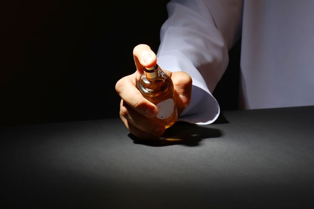 Mão segurando frasco de perfume árabe